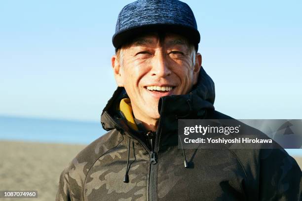 portrait of man in beach on the morning glow coast. - japanese old man foto e immagini stock