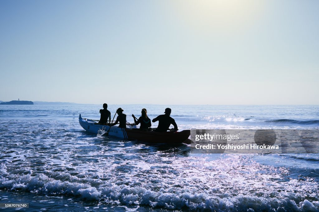 Men and women playing canoe at Pacific Ocean.