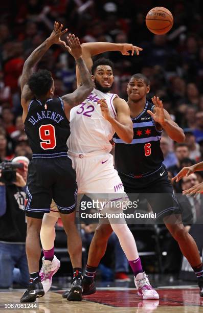 Karl-Anthony Towns of the Minnesota Timberwolves passes over his head under pressure from Antonio Blakeney and Cristiano Felicio of the Chicago Bulls...
