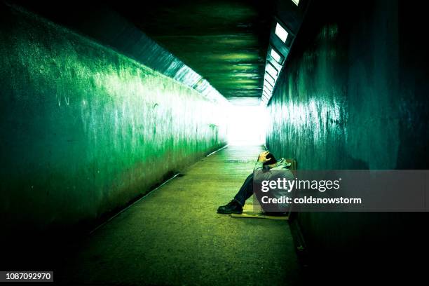 homeless depressed man sitting in cold subway tunnel - drug abuse stock pictures, royalty-free photos & images