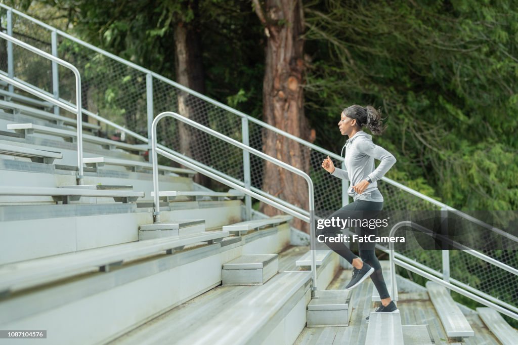 Female track athlete trains on stadium bleachers