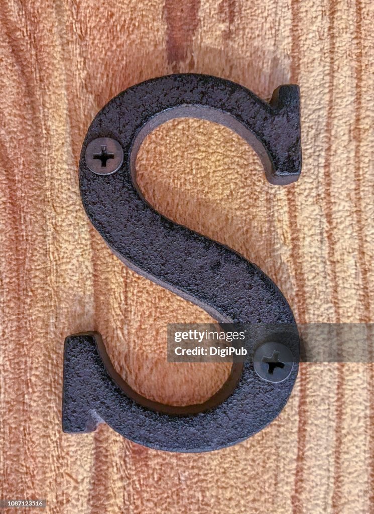 Cast iron capital letter S on wood