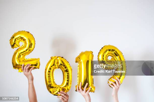 hands holding 2019 gold-colored balloon - 2019 photos et images de collection