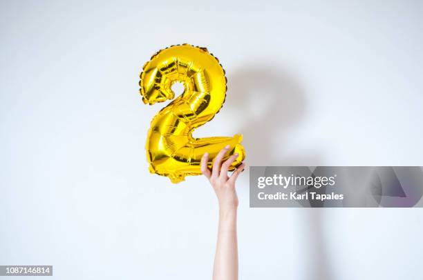 holding an inflatable number 2 balloon - number 2 balloon stock pictures, royalty-free photos & images