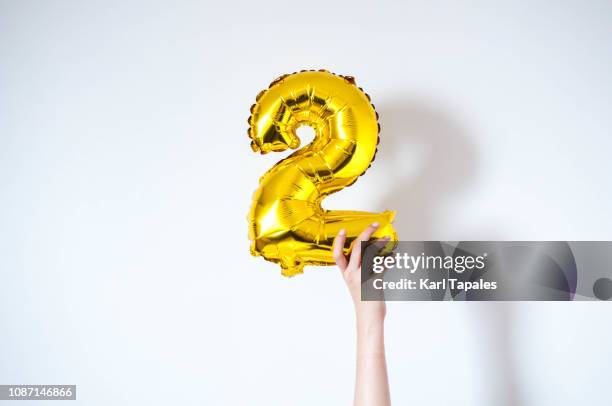 holding an inflatable number 2 balloon - number 2 stockfoto's en -beelden