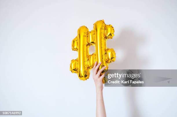 a golden-colored balloon symbol hashtag - hashtag foto e immagini stock