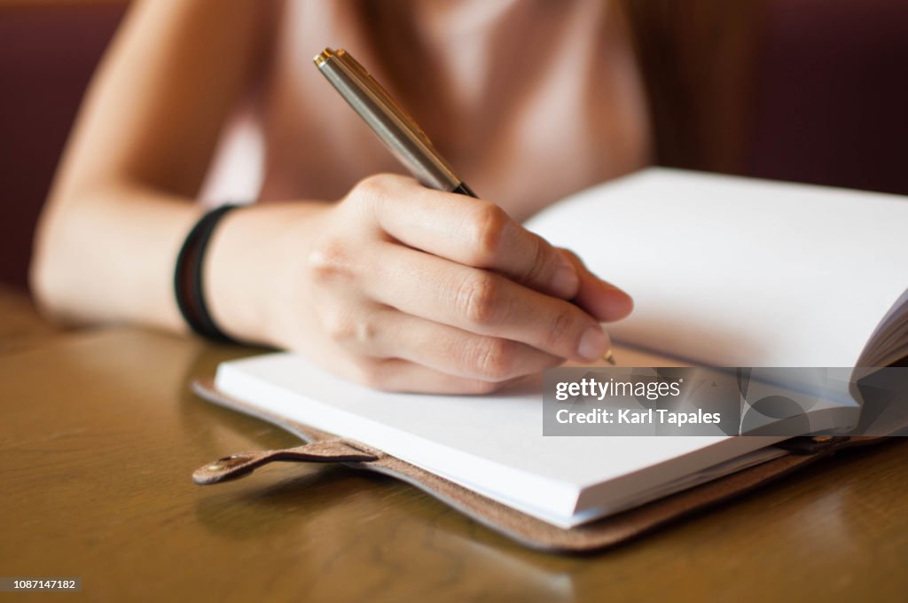 A young woman is writing on her personal organizer