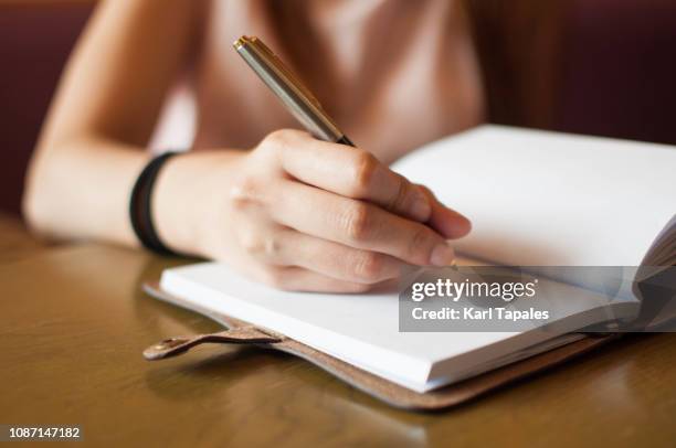 a young woman is writing on her personal organizer - hand pen photos et images de collection