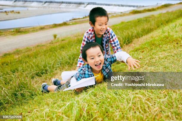 siblings play at river bank with air plane. - embankment stock-fotos und bilder