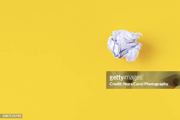 crumpled paper ball on yellow background - prop stockfoto's en -beelden