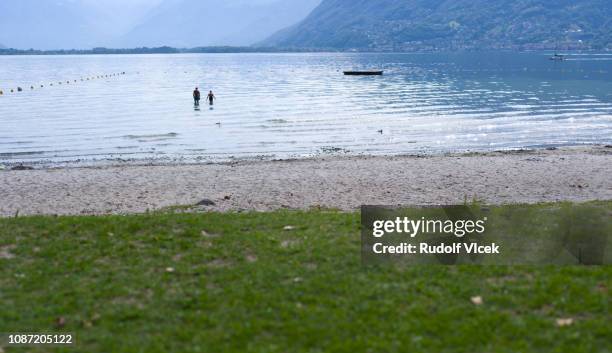 lago maggiore beach, two people silhouettes in water - see lago maggiore stock-fotos und bilder