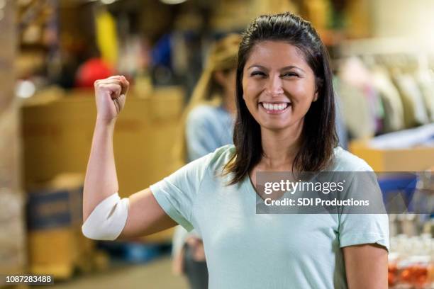 woman flexes muscles after donating blood - blood test stock pictures, royalty-free photos & images