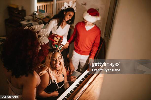 generation z friends christmas party singing at piano - carol singer stock pictures, royalty-free photos & images
