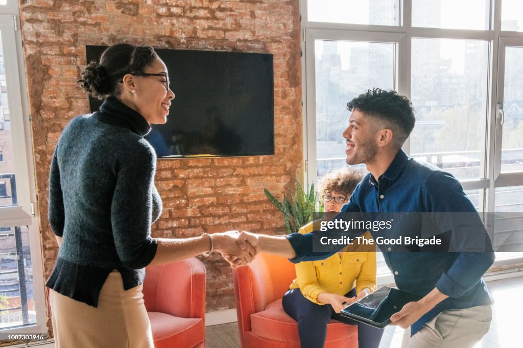 Smiling business man shaking hands with client in office