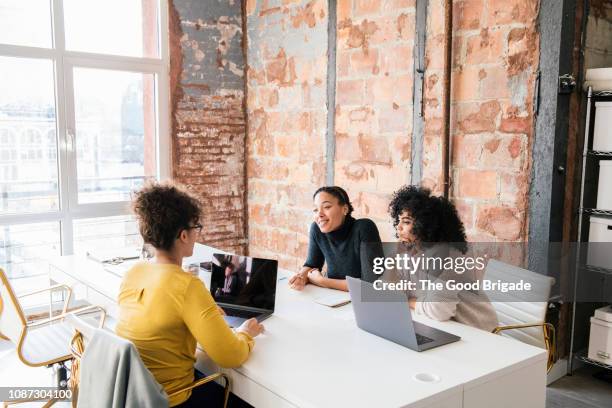 female colleagues working in open plan office - brick wall business person stock pictures, royalty-free photos & images