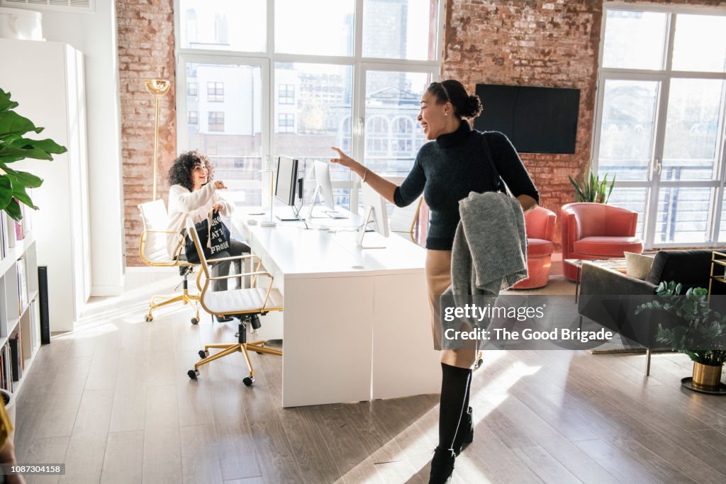 Woman waving goodbye to colleague in office