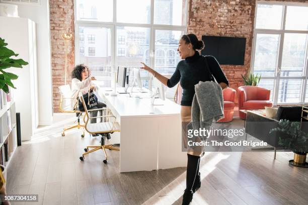 woman waving goodbye to colleague in office - the end stock pictures, royalty-free photos & images