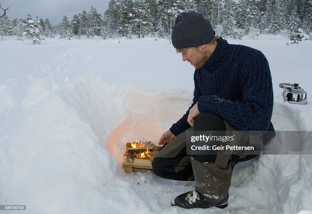 Man building fire in winter landscape