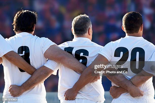 rugby team standing with arms locked, rear view - rugby union team fotografías e imágenes de stock