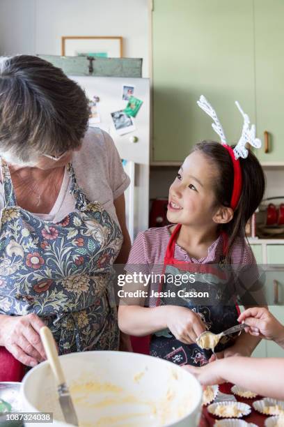 girl looking at grandmother whilst preparing food for christmas - auckland food stock pictures, royalty-free photos & images