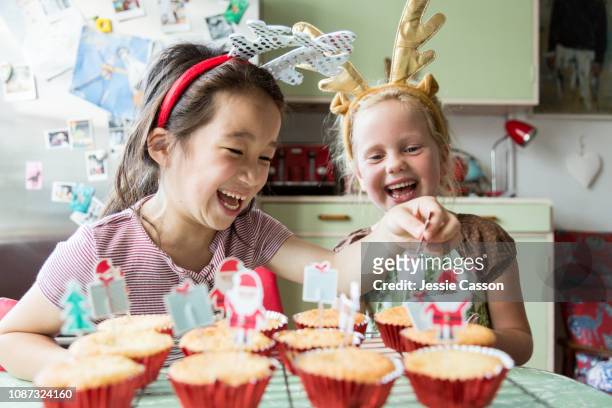 Girls laugh whilst decorating Christmas cupcakes