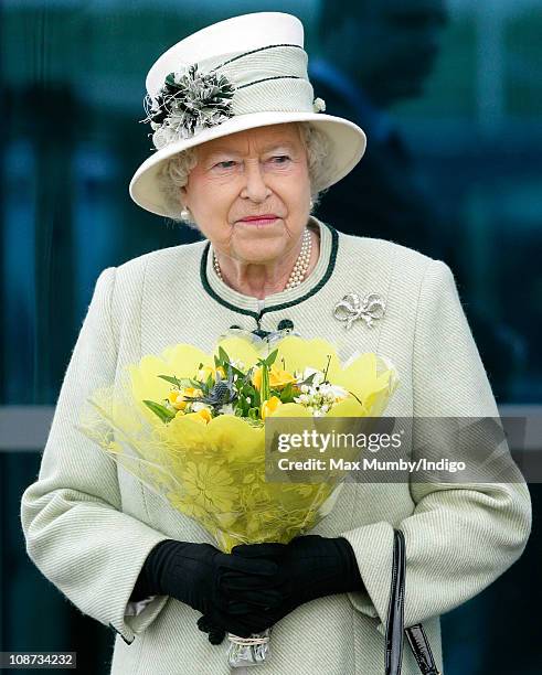 Queen Elizabeth II carries a bouquet of flowers as she leaves Palm Paper mill on February 2, 2011 in Norwich, England. The Queen and the Duke of...
