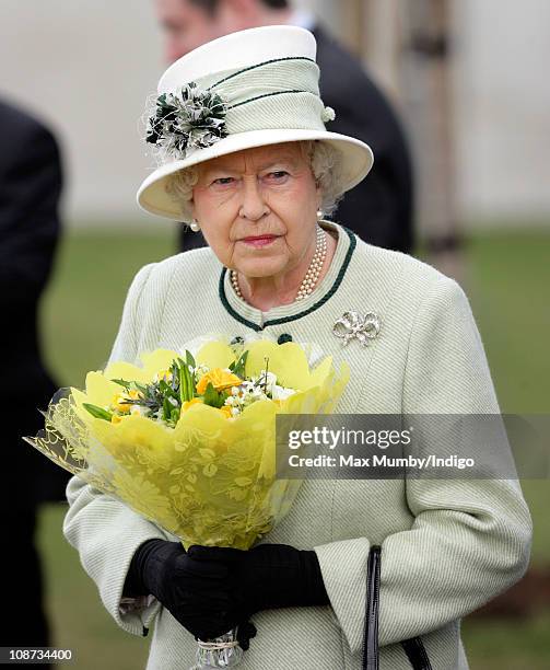 Queen Elizabeth II carries a bouquet of flowers as she leaves Palm Paper mill on February 2, 2011 in Norwich, England. The Queen and the Duke of...