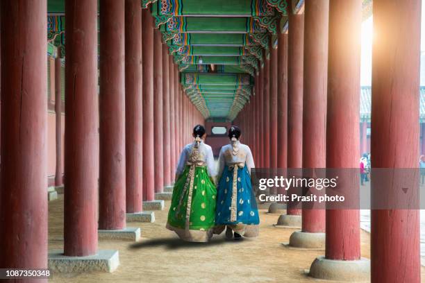 asian korean woman dressed hanbok in traditional dress walking in gyeongbokgung palace in seoul, south korea. - gyeongbokgung stock-fotos und bilder