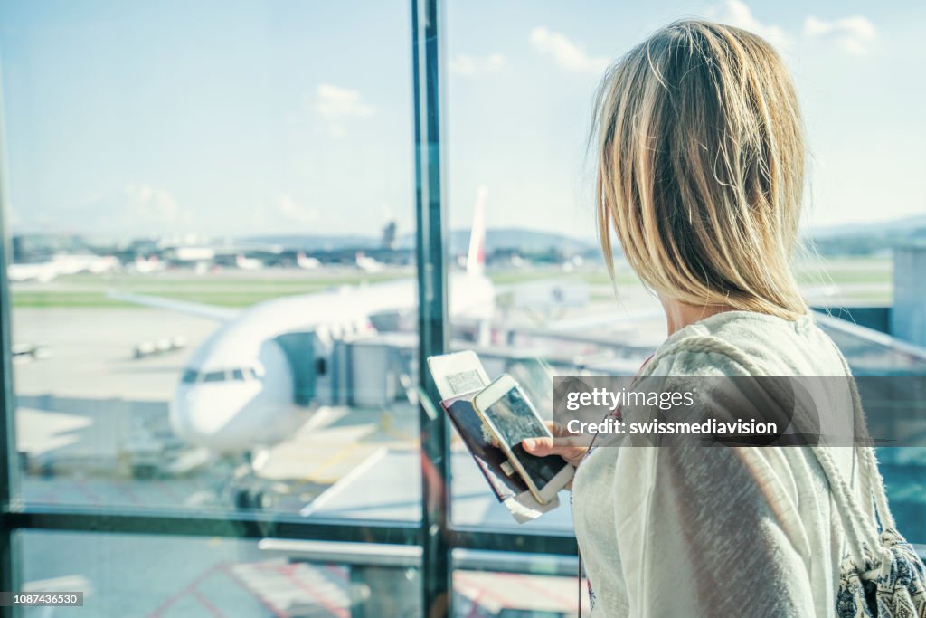 Female at airport in terminal waiting for departure flight