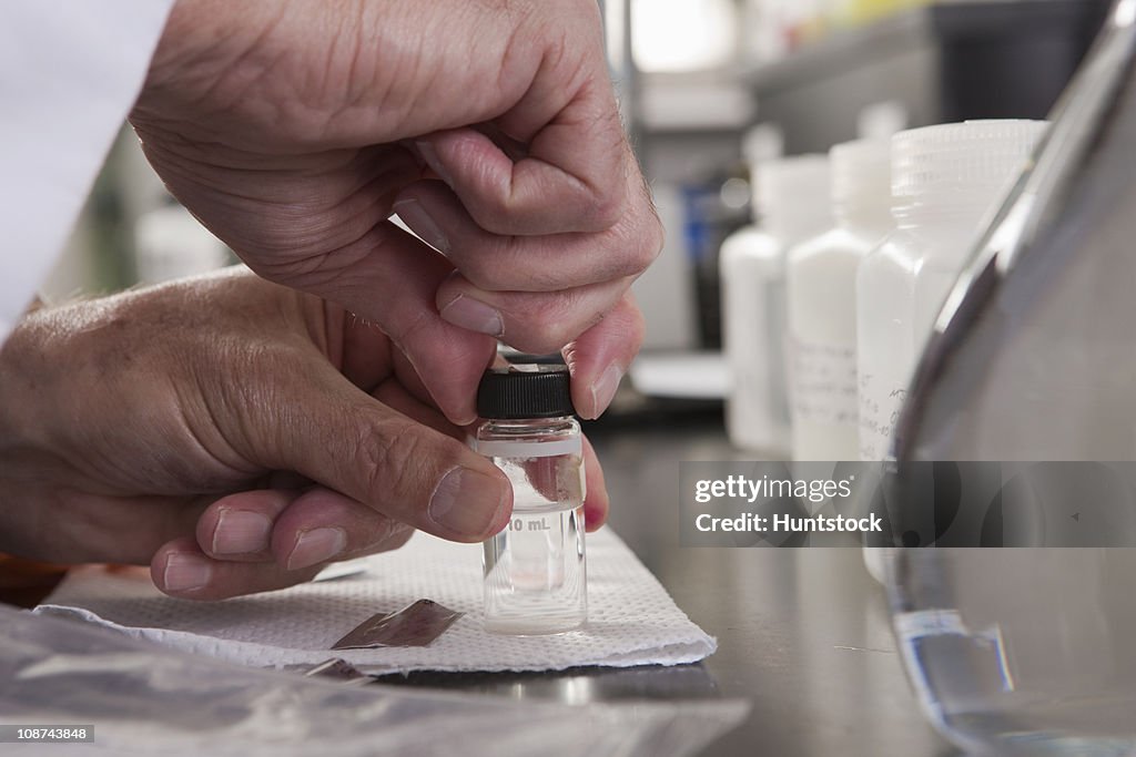 Scientist sealing sample bottles after adding chemicals in the laboratory of water treatment plant