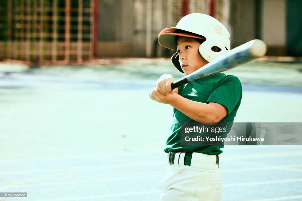 Kids (8-9) swinging baseball bat at ball