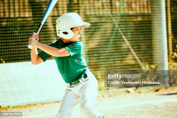 boy (8-9) swinging baseball bat at ball - japanese baseball players strike stock pictures, royalty-free photos & images