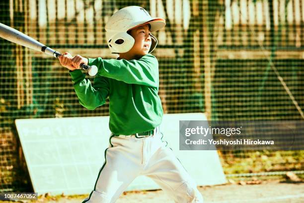 boy (6-7) swinging baseball bat at ball - batting sports activity ストックフォトと画像