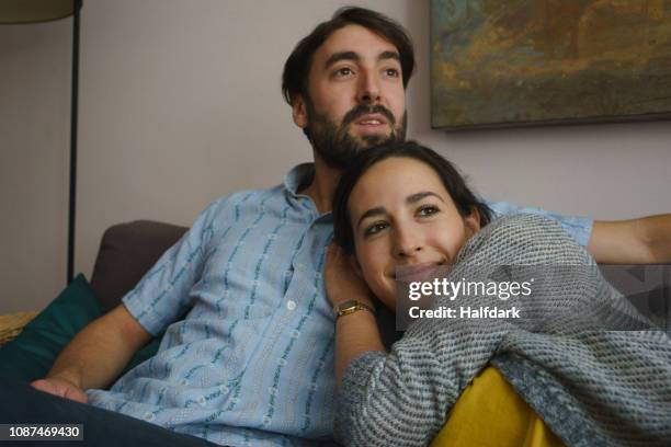 smiling couple relaxing on living room sofa - husband stock pictures, royalty-free photos & images