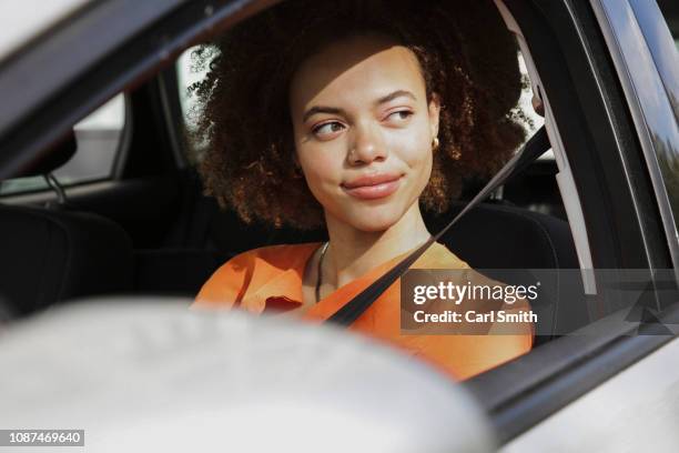 confident young woman driving car - fahren stock-fotos und bilder