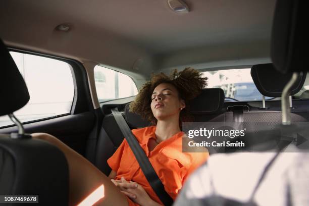 tired young woman sleeping in back seat of car - sleeping in car stockfoto's en -beelden