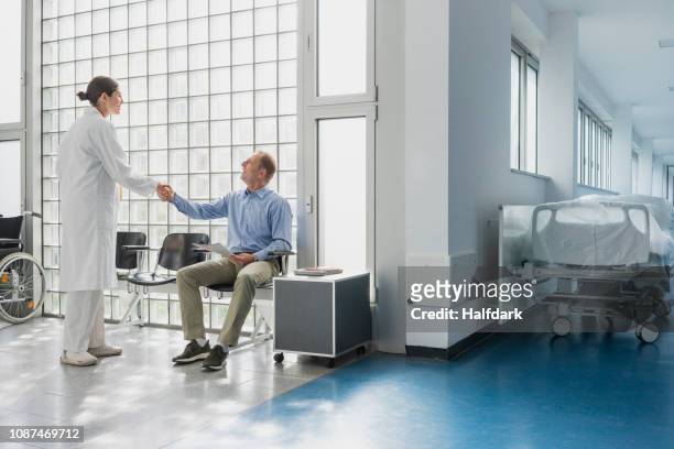 doctor greeting, shaking hands with patient in hospital waiting room - patients in doctors waiting room stock pictures, royalty-free photos & images