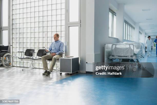 male patient reading magazine, waiting in hospital waiting room - waiting room stock pictures, royalty-free photos & images