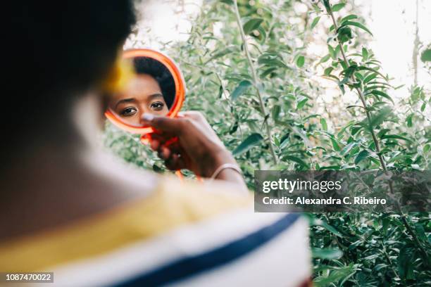 young woman looking in compact mirror - powder compact 個照片及圖片檔