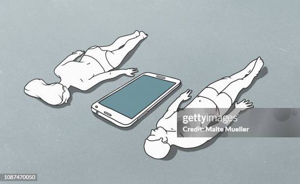 large mobile phone between female figure lying face down and male figure lying down on back - digital devices beside each other bildbanksfoton och bilder