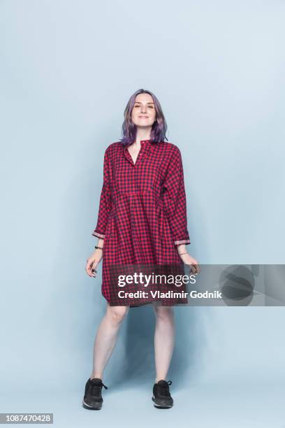 portrait confident and fashionable young woman against blue background - checked dress stock pictures, royalty-free photos & images