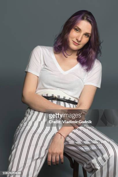 portrait of a confident young woman sitting on a chair - purple hair fotografías e imágenes de stock
