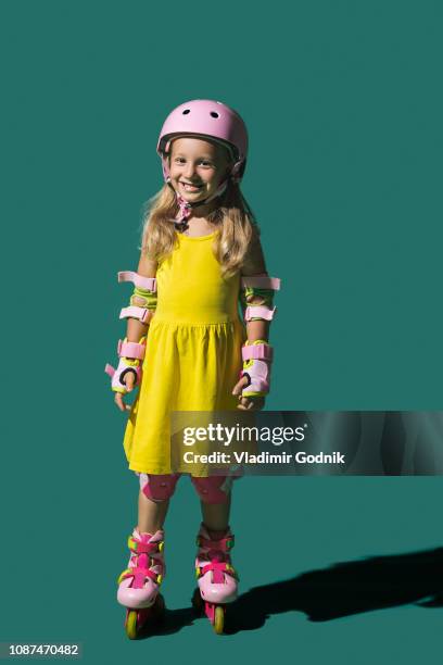 portrait smiling girl roller skating on green background - inline skate stock pictures, royalty-free photos & images