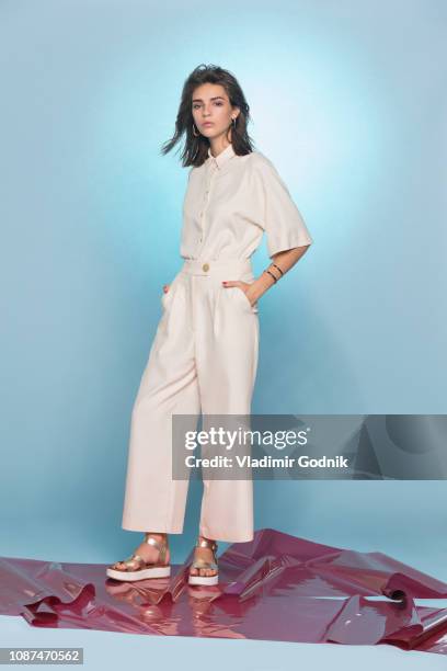 portrait of female fashion model posing against blue background - beige suit stock pictures, royalty-free photos & images