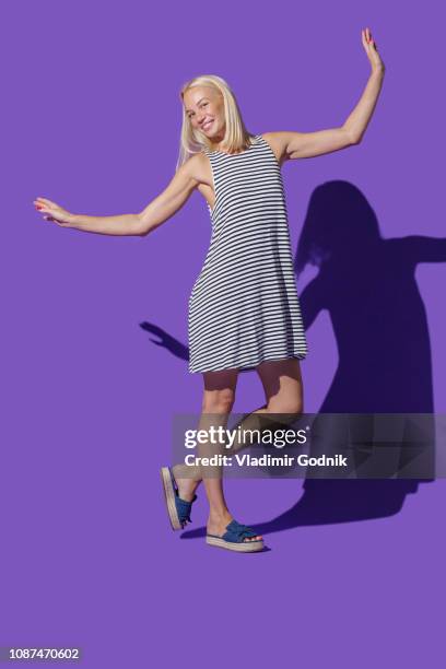 portrait carefree woman in striped dress against purple background - portrait studio purple background stock pictures, royalty-free photos & images