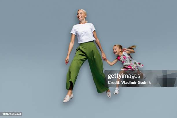 mother and daughter running on blue background - laufen freisteller stock-fotos und bilder