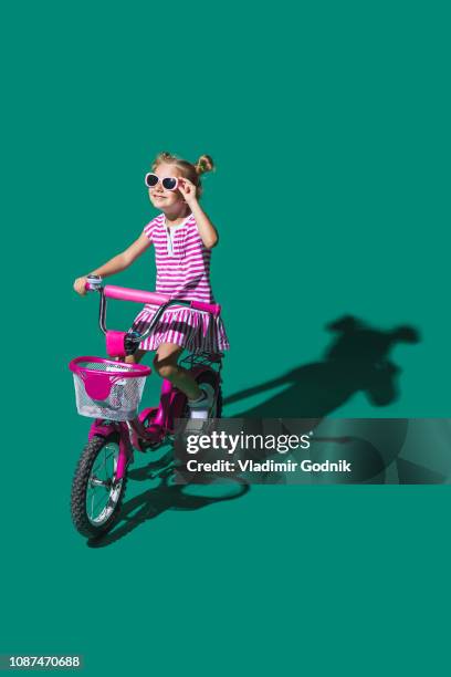 girl in sunglasses bike riding against green background - farbbild stock-fotos und bilder