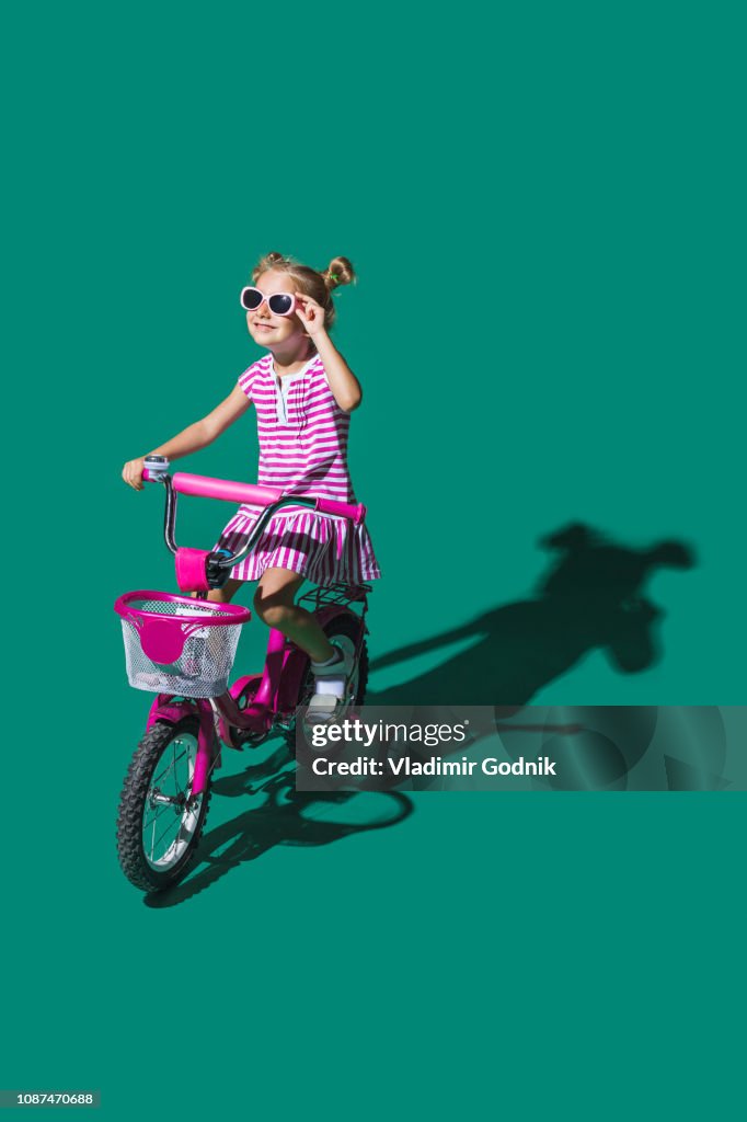 Girl in sunglasses bike riding against green background