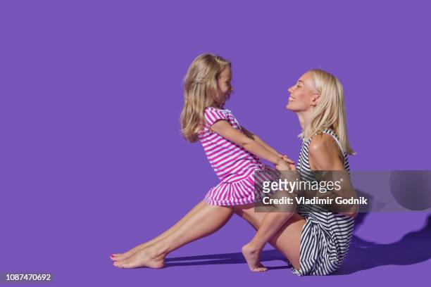 mother and daughter in striped dresses on purple background - kids side view isolated stockfoto's en -beelden