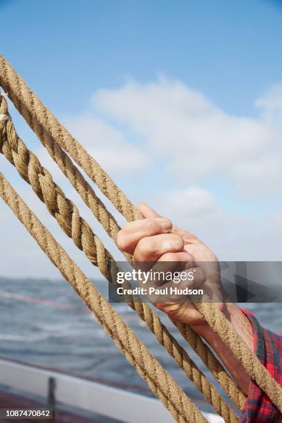 man holding rope, adjusting rigging on boat - pull foto e immagini stock